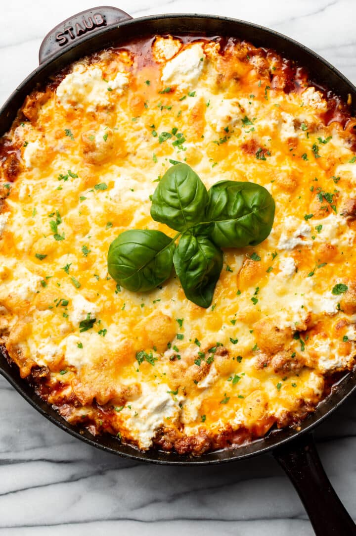 a skillet with cheesy lasagna and basil