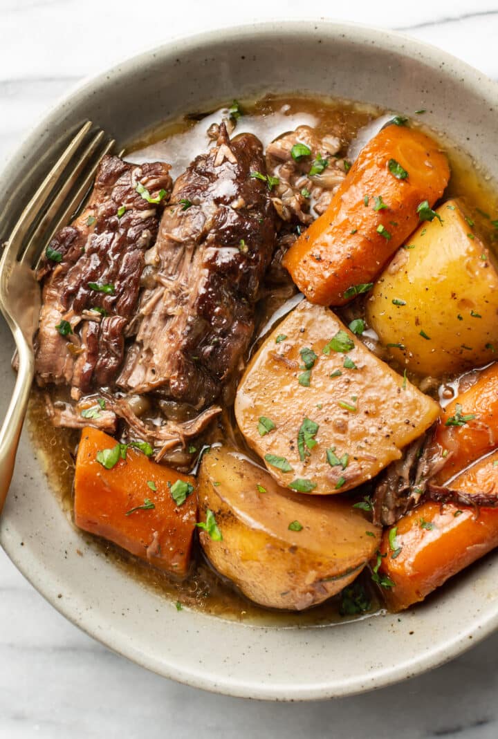 a bowl of pot roast with a fork