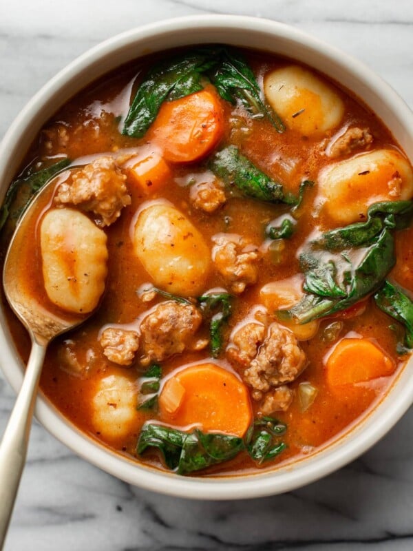 a bowl of sausage gnocchi soup with a spoon