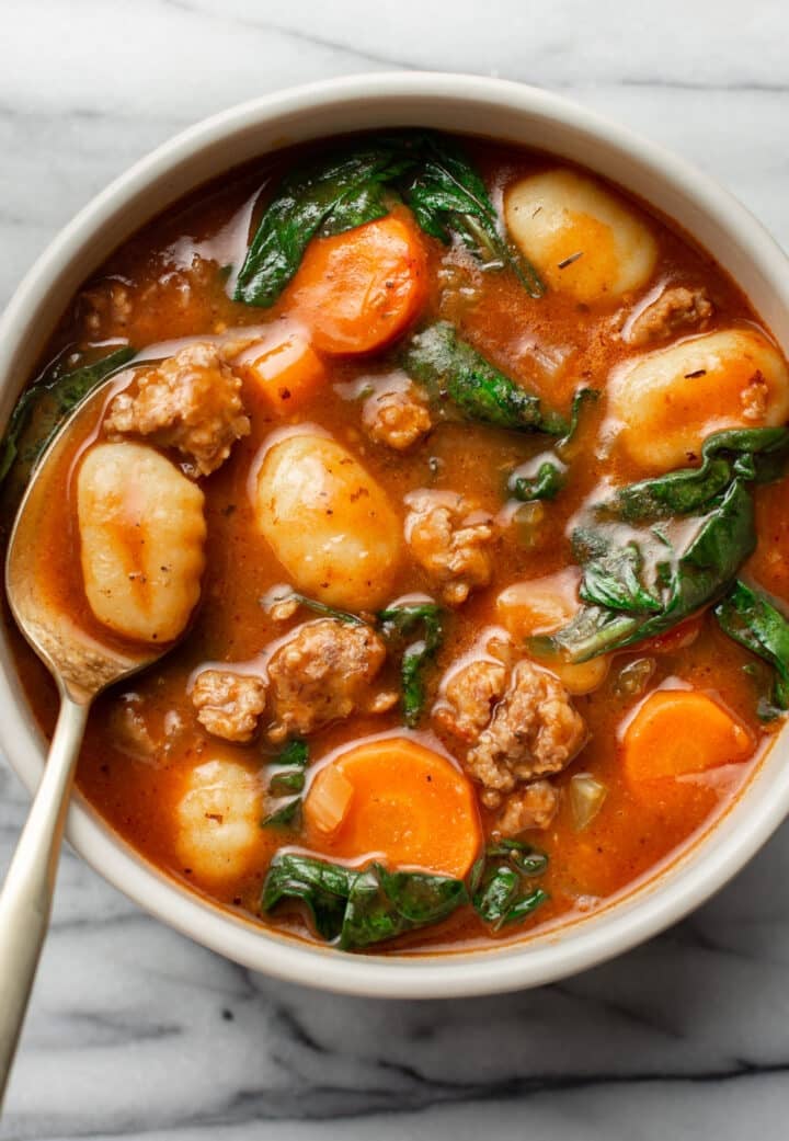 a bowl of sausage gnocchi soup with a spoon