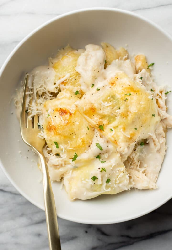 a bowl with a portion of chicken ravioli bake with a fork