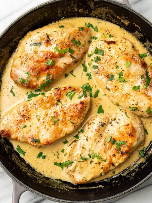 a skillet with four chicken cutlets in a creamy tarragon sauce
