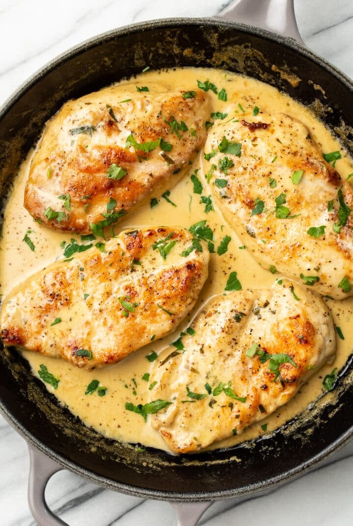 a skillet with four chicken cutlets in a creamy tarragon sauce