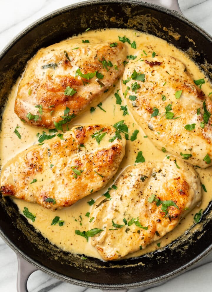 a skillet with four chicken cutlets in a creamy tarragon sauce
