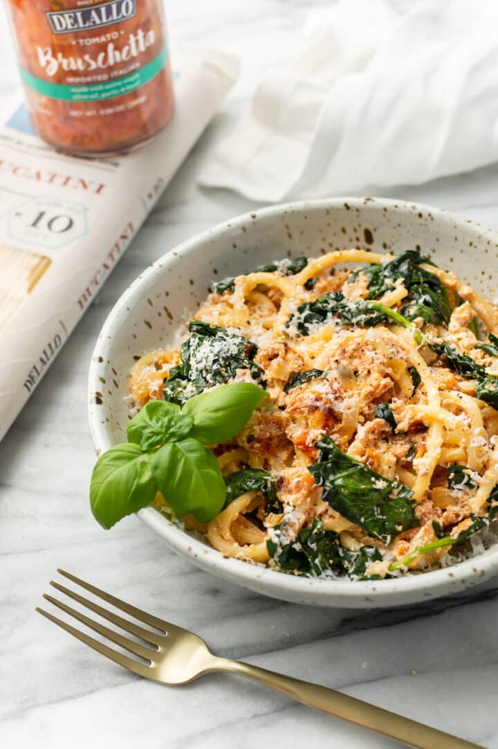 baked feta pasta in a bowl with a jar of bruschetta