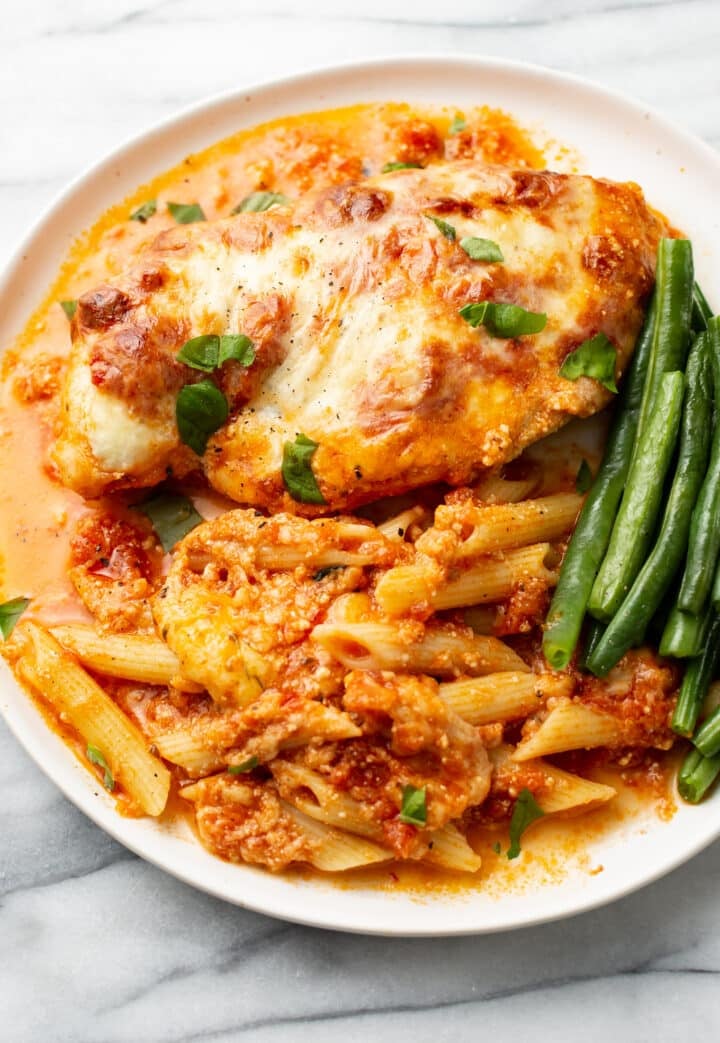 a plate with baked ricotta chicken, green beans, and penne