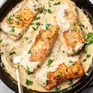 creamy boursin salmon in a cast iron skillet with a spoon