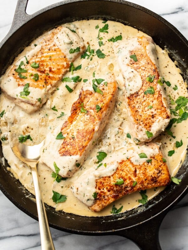 creamy boursin salmon in a cast iron skillet with a spoon