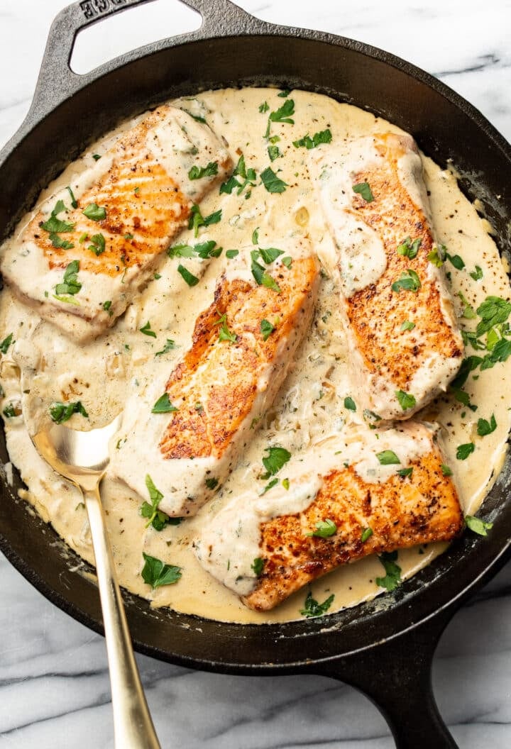 creamy boursin salmon in a cast iron skillet with a spoon