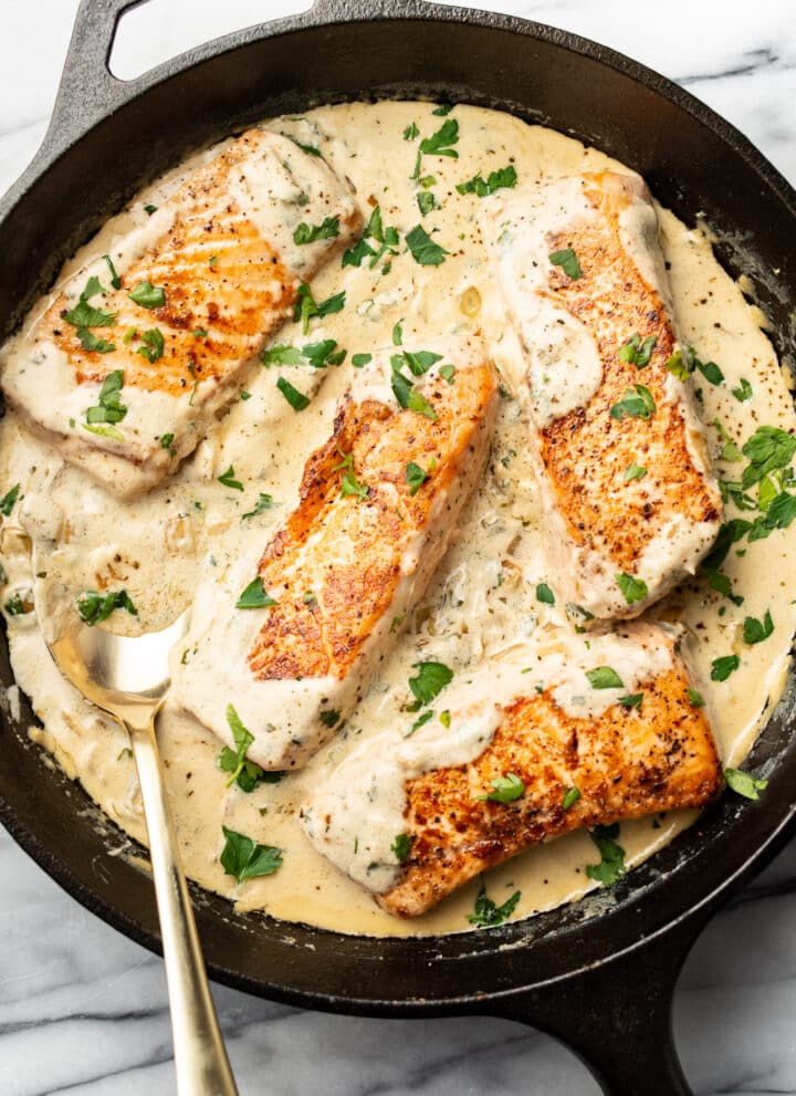 creamy boursin salmon in a cast iron skillet with a spoon