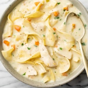 a bowl of creamy chicken noodle soup with a spoon