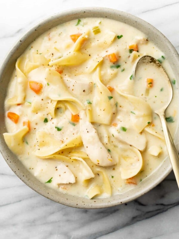 a bowl of creamy chicken noodle soup with a spoon