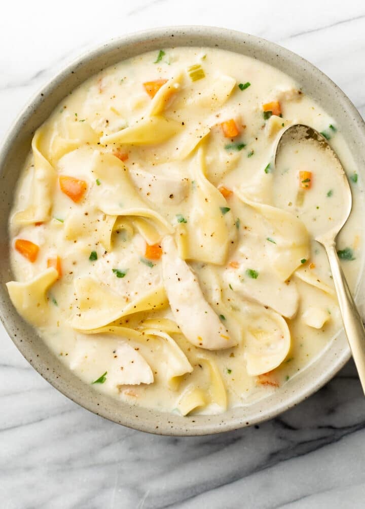 a bowl of creamy chicken noodle soup with a spoon