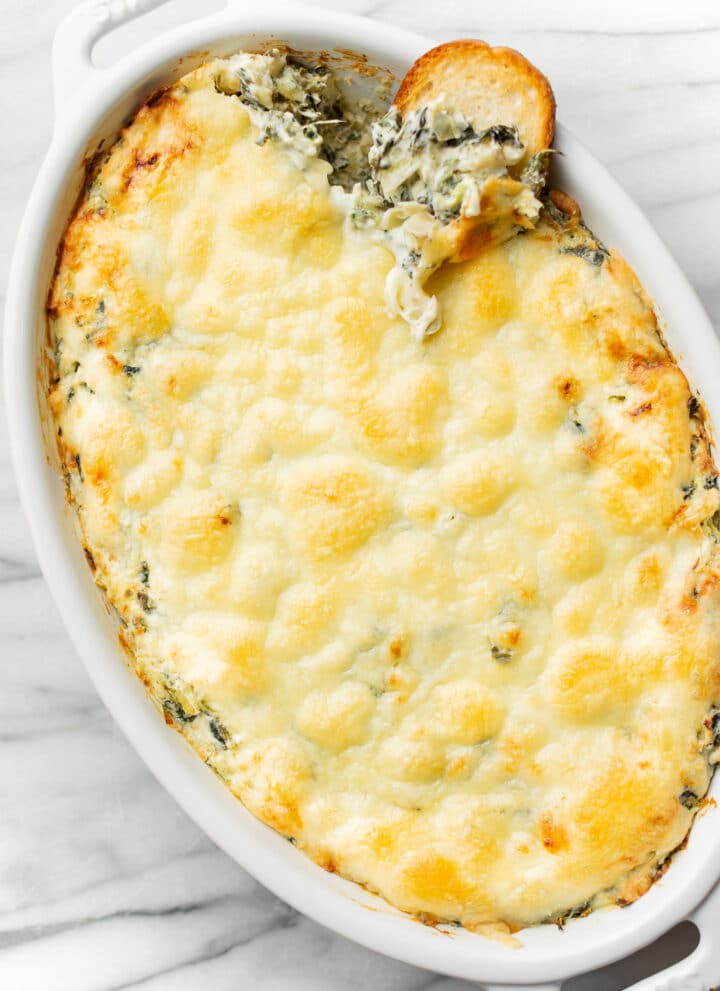 a baking dish with spinach artichoke dip