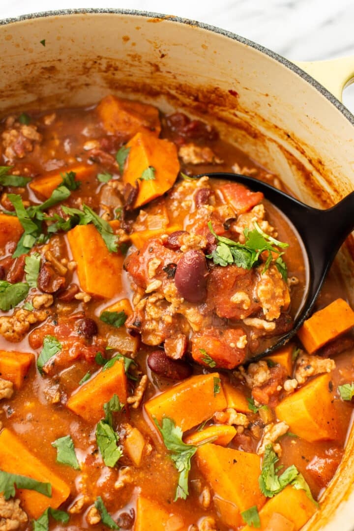 a pot of turkey chili with a ladle