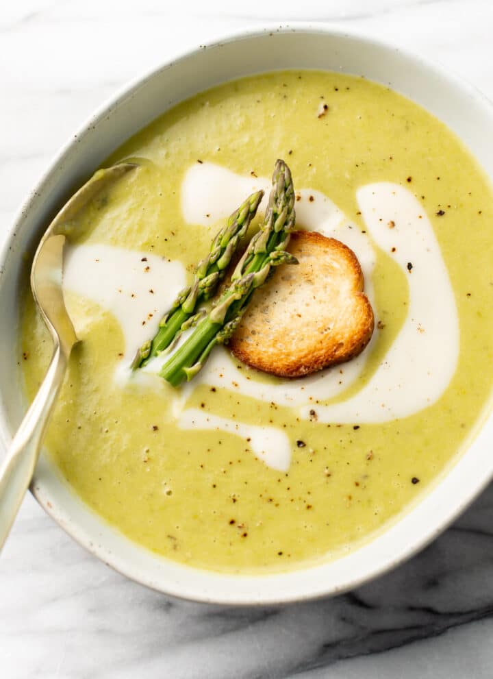 a bowl of asparagus soup with a spoon