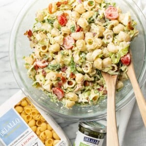 a salad bowl with BLT pasta salad next to delallo products