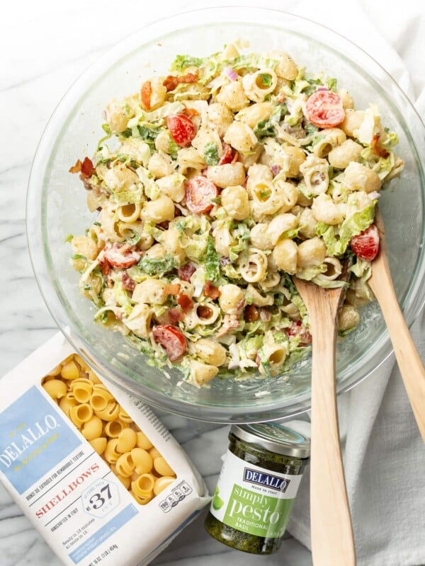 a salad bowl with BLT pasta salad next to delallo products