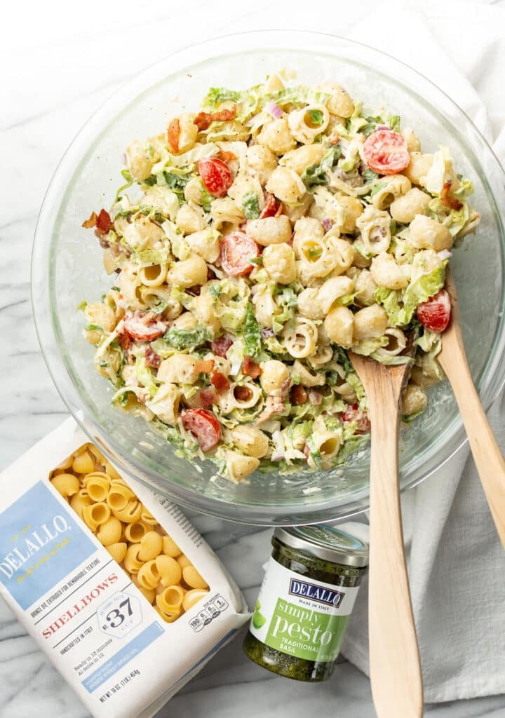 a salad bowl with BLT pasta salad next to delallo products