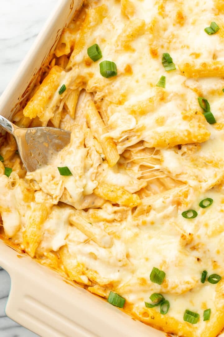 a baking dish with buffalo chicken casserole and a serving spoon