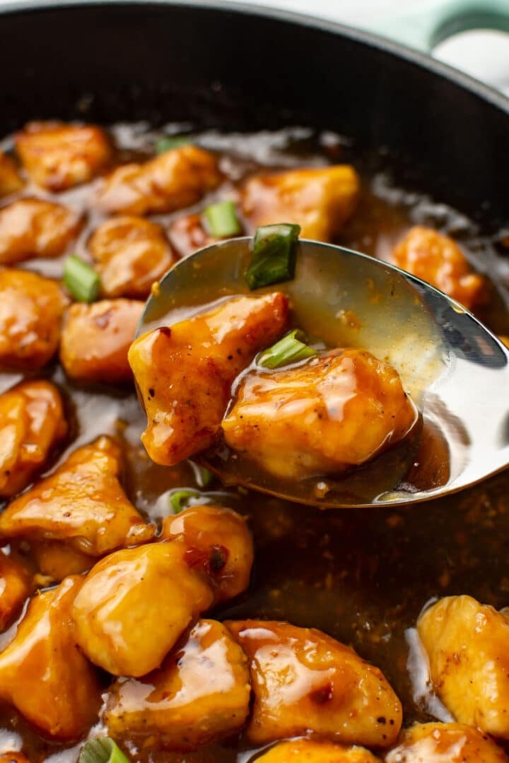 closeup of a skillet with a spoonful of orange chicken