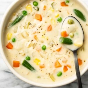 a bowl of potato vegetable soup with a spoon