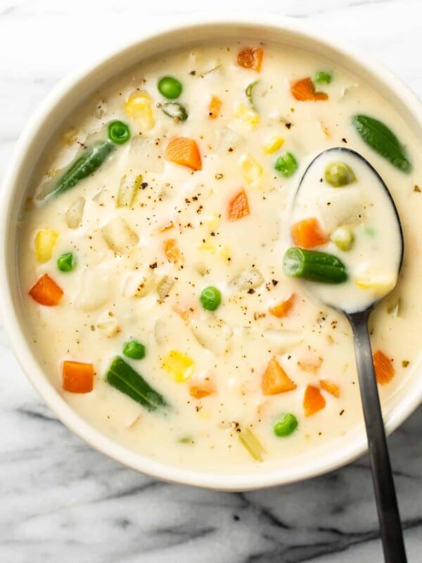 a bowl of potato vegetable soup with a spoon