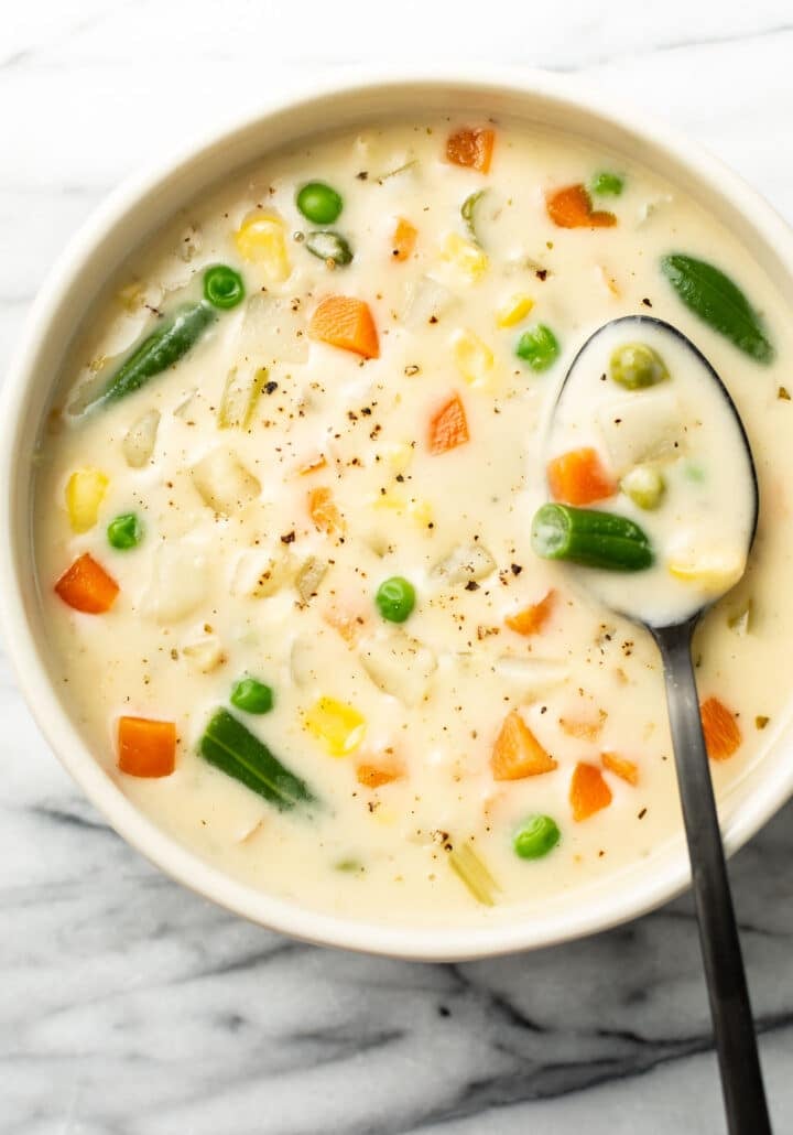 a bowl of potato vegetable soup with a spoon