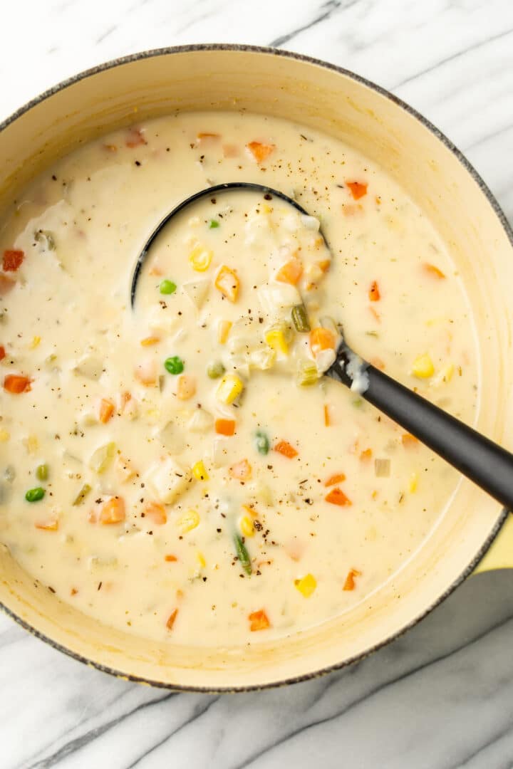 a dutch oven with potato vegetable soup and a ladle