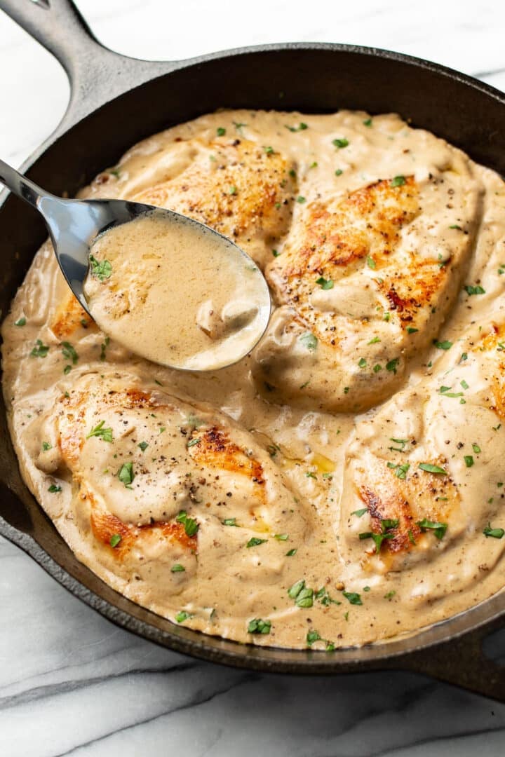 a skillet with cream of mushroom chicken and a serving spoon