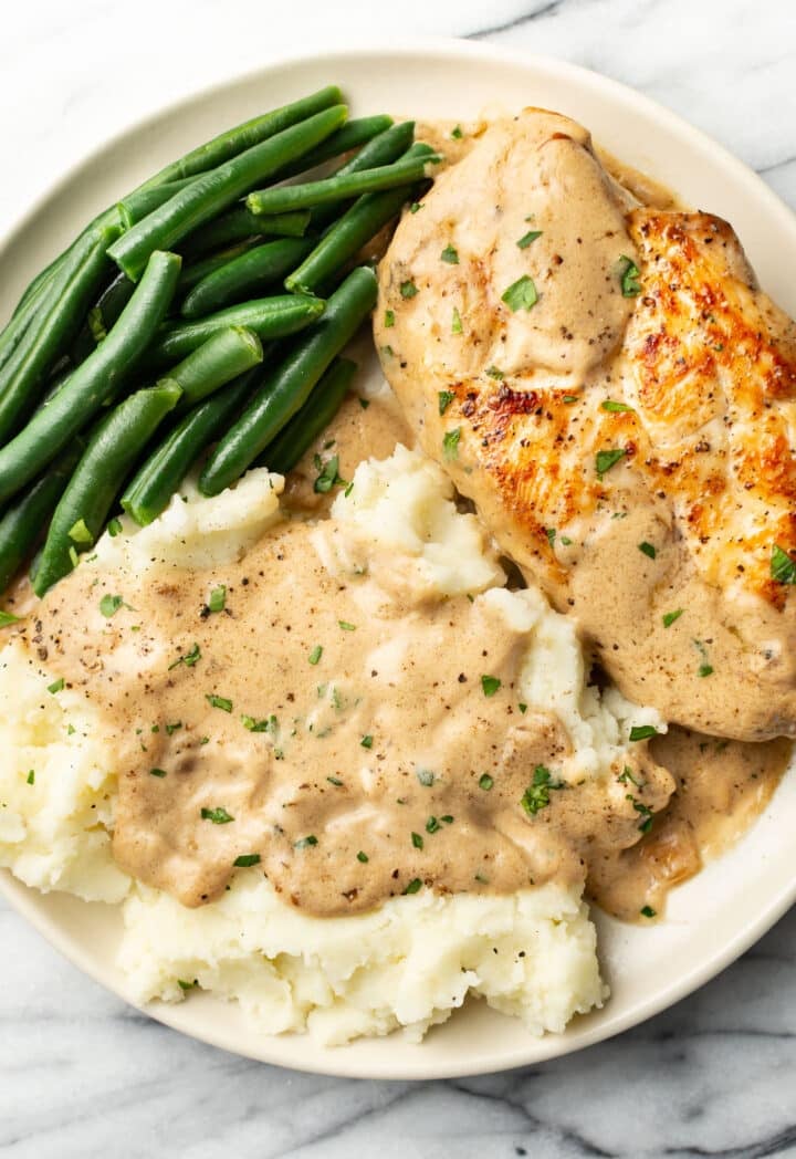 a plate with chicken in cream of mushroom sauce, green beans, and mashed potatoes