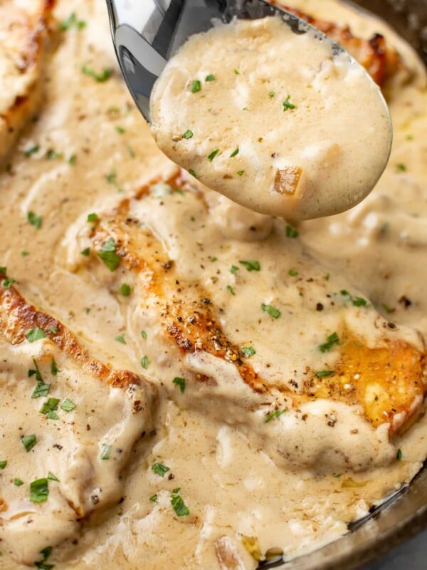 closeup of a spoonful of sauce over a skillet of cream of mushroom soup pork chops