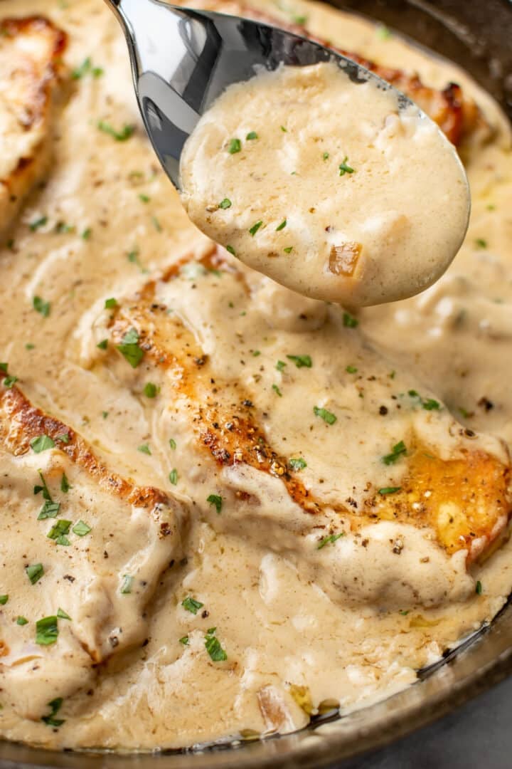 closeup of a spoonful of sauce over a skillet of cream of mushroom soup pork chops