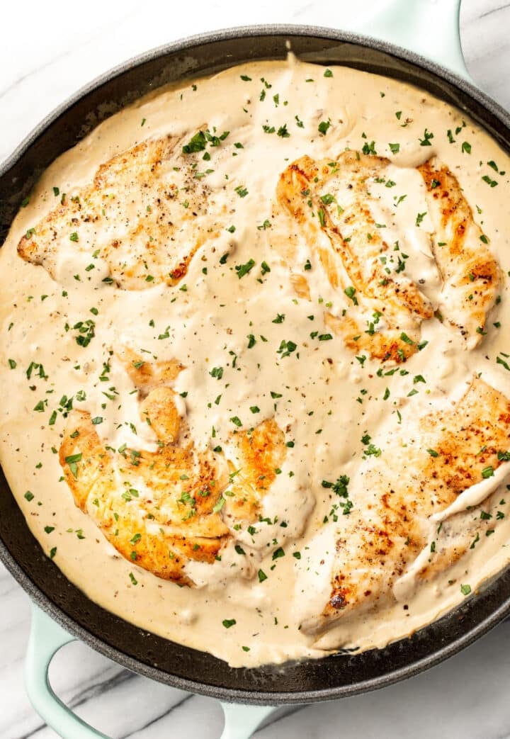 a cast iron skillet with chicken in cream cheese sauce
