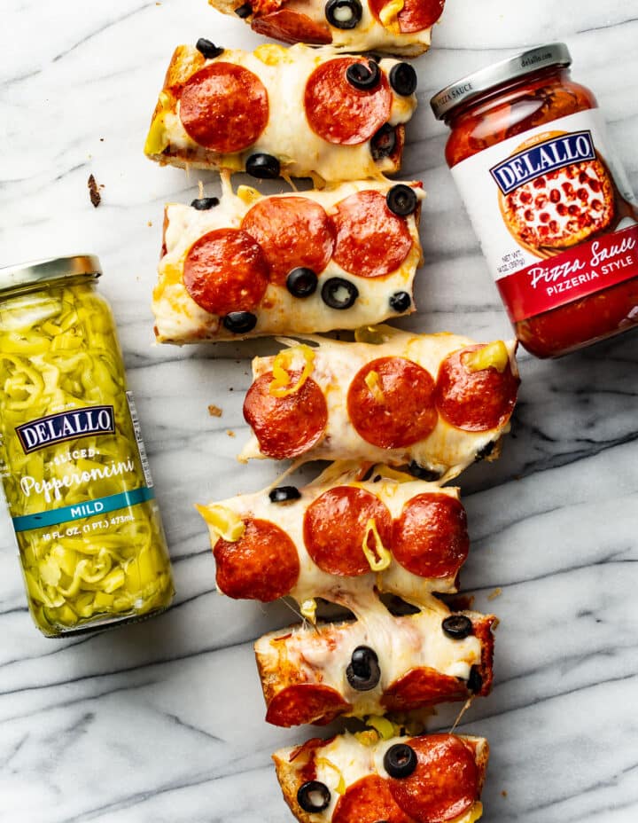 several slices of french bread pizza next to jars of ingredients