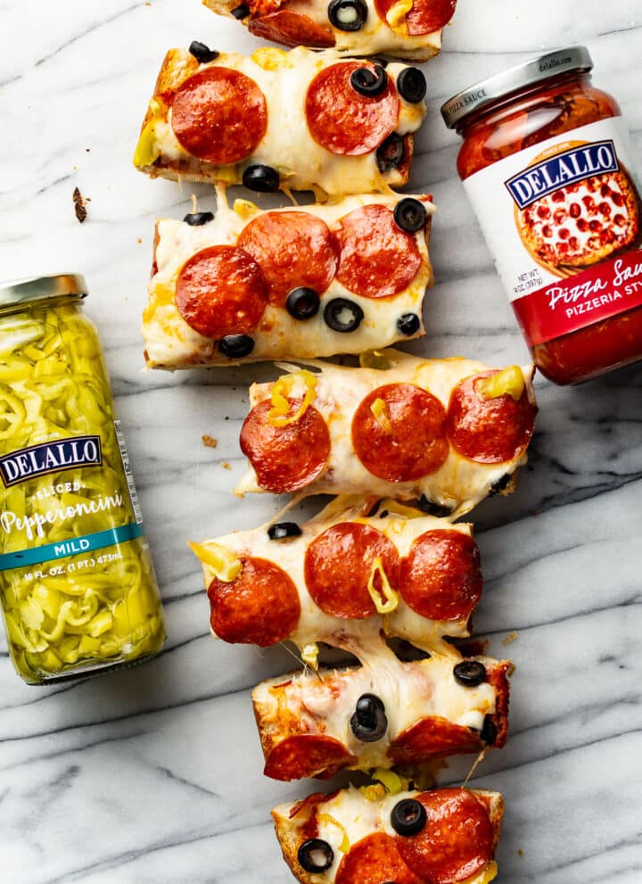 several slices of french bread pizza next to jars of ingredients