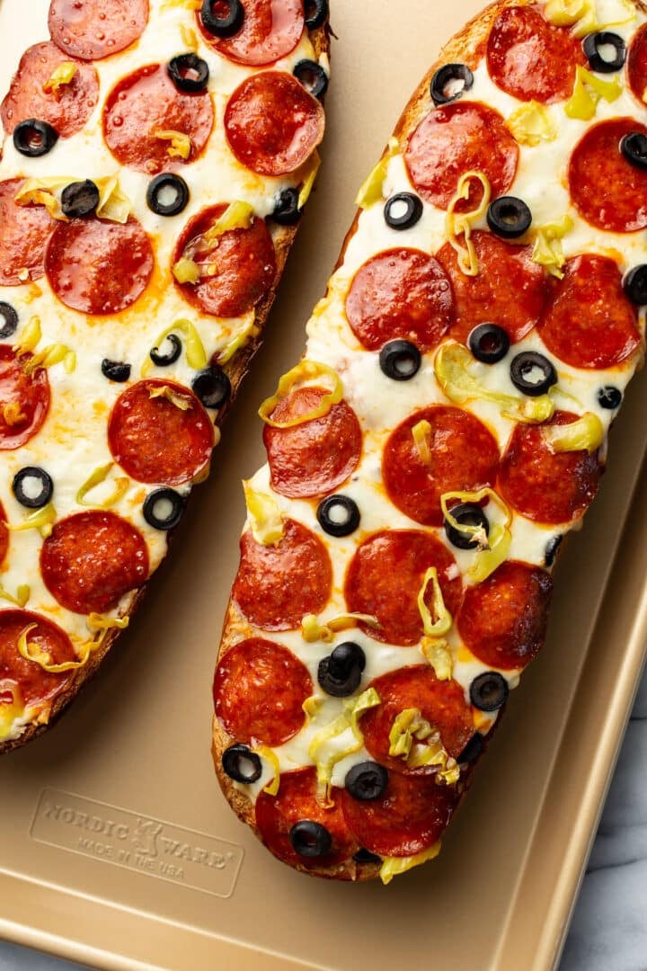 two halves of a loaf of french bread pizza on a baking tray