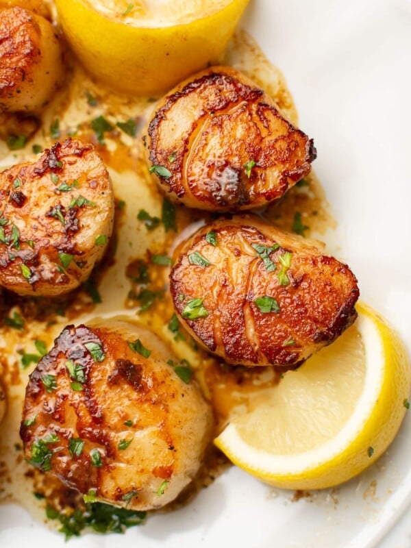 a plate with pan seared scallops next to lemon wedges