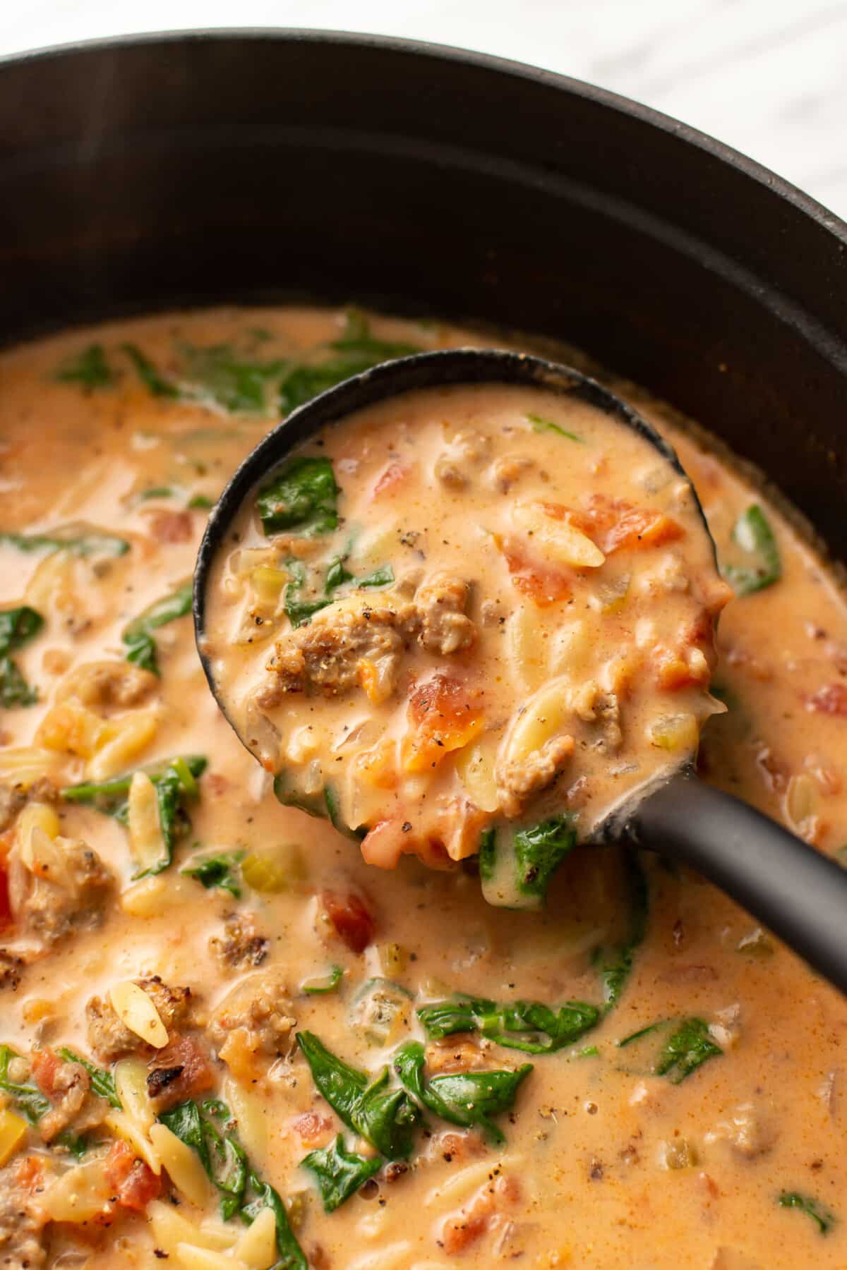 a ladle with italian sausage orzo soup