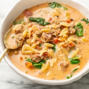 a bowl of italian sausage orzo soup with a spoon