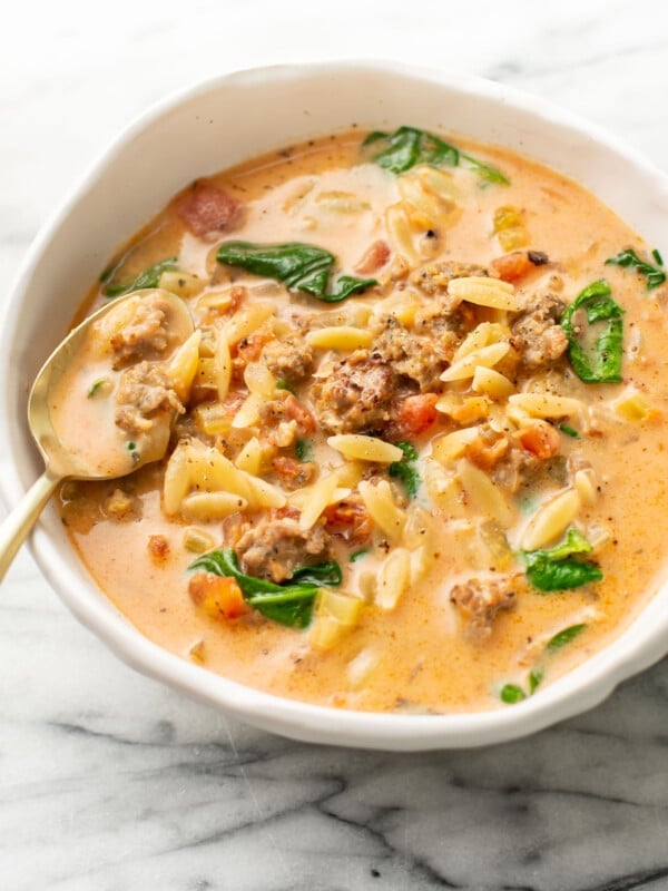 a bowl of italian sausage orzo soup with a spoon