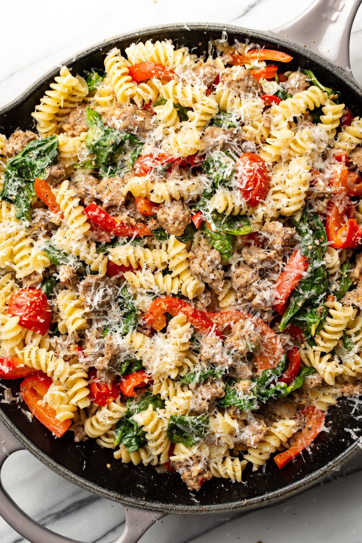 a skillet with sausage and vegetable pasta