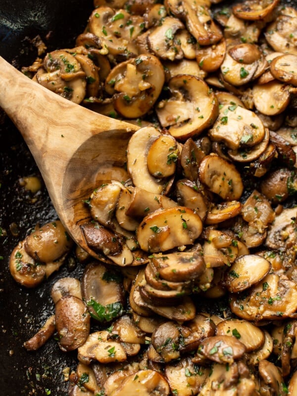 a skillet with sauteed mushrooms and a wooden spoon