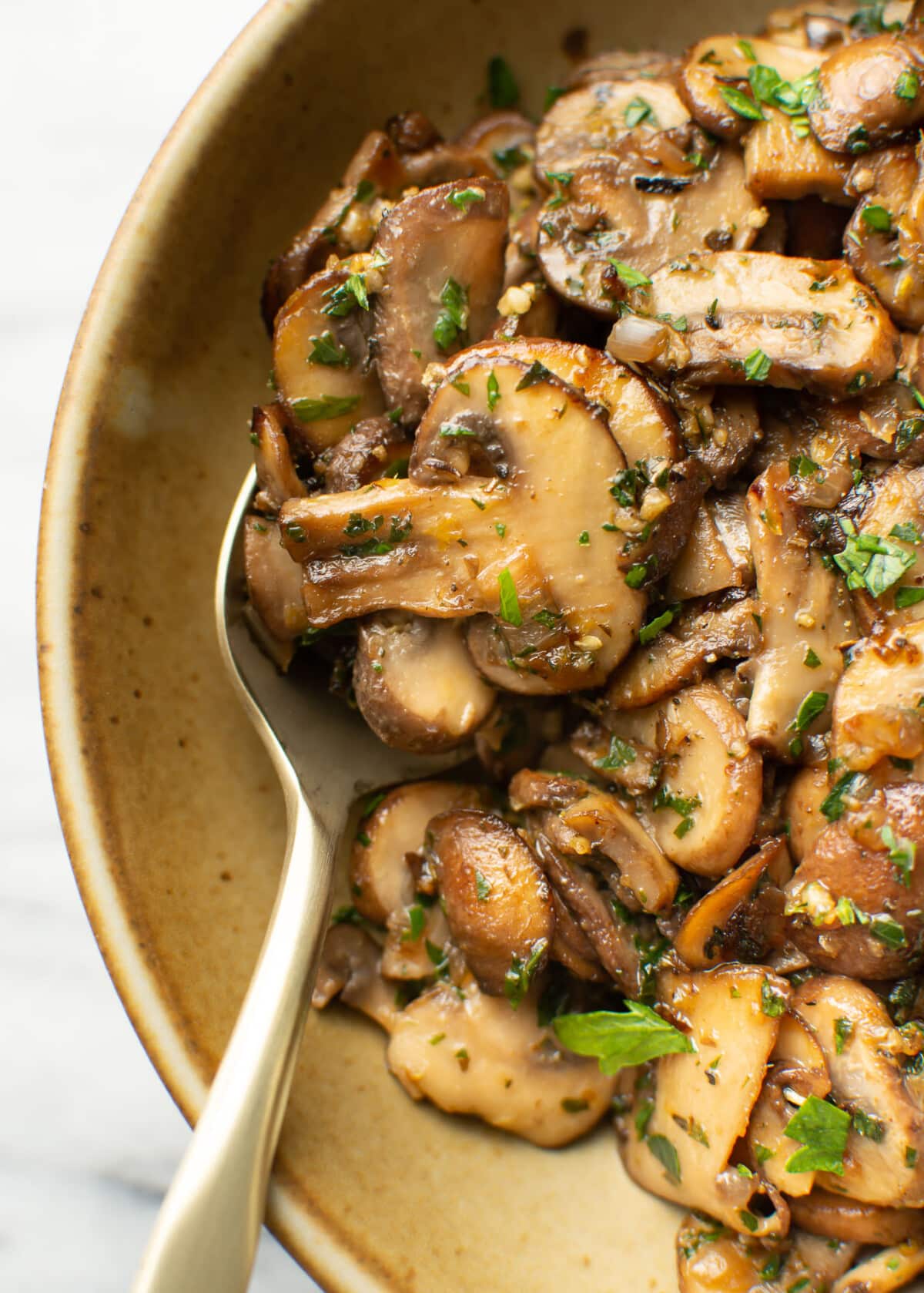 a bowl with sauteed mushrooms and a spoon