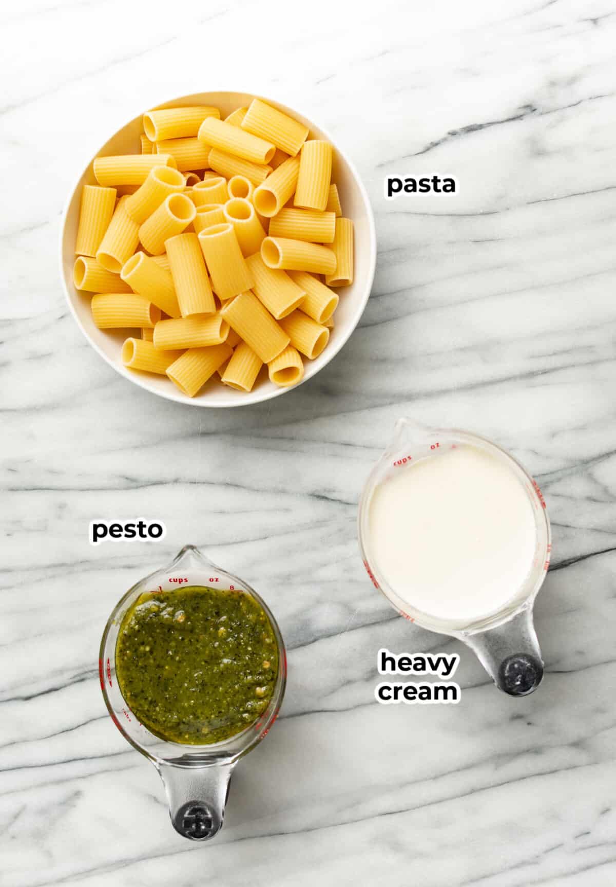 ingredients for pesto pasta in a prep bowl and measuring cups