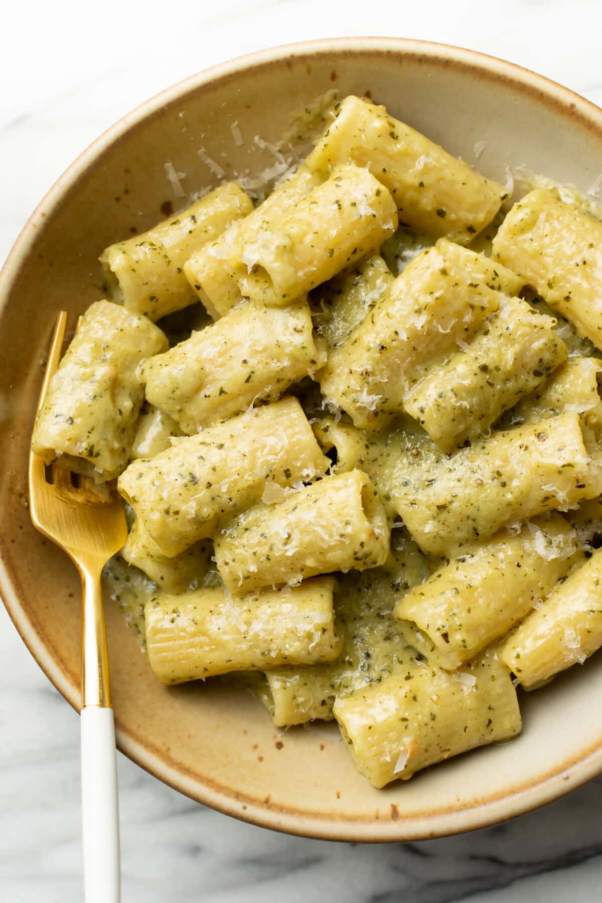 a bowl of pesto pasta with a fork