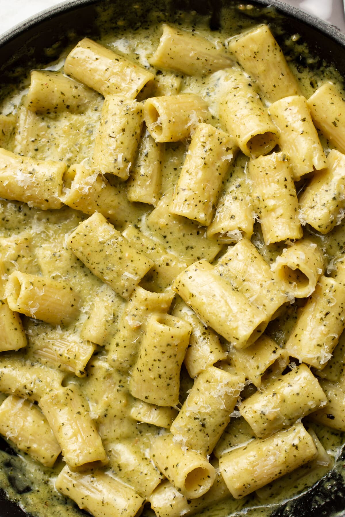 a skillet with rigatoni in a creamy pesto sauce