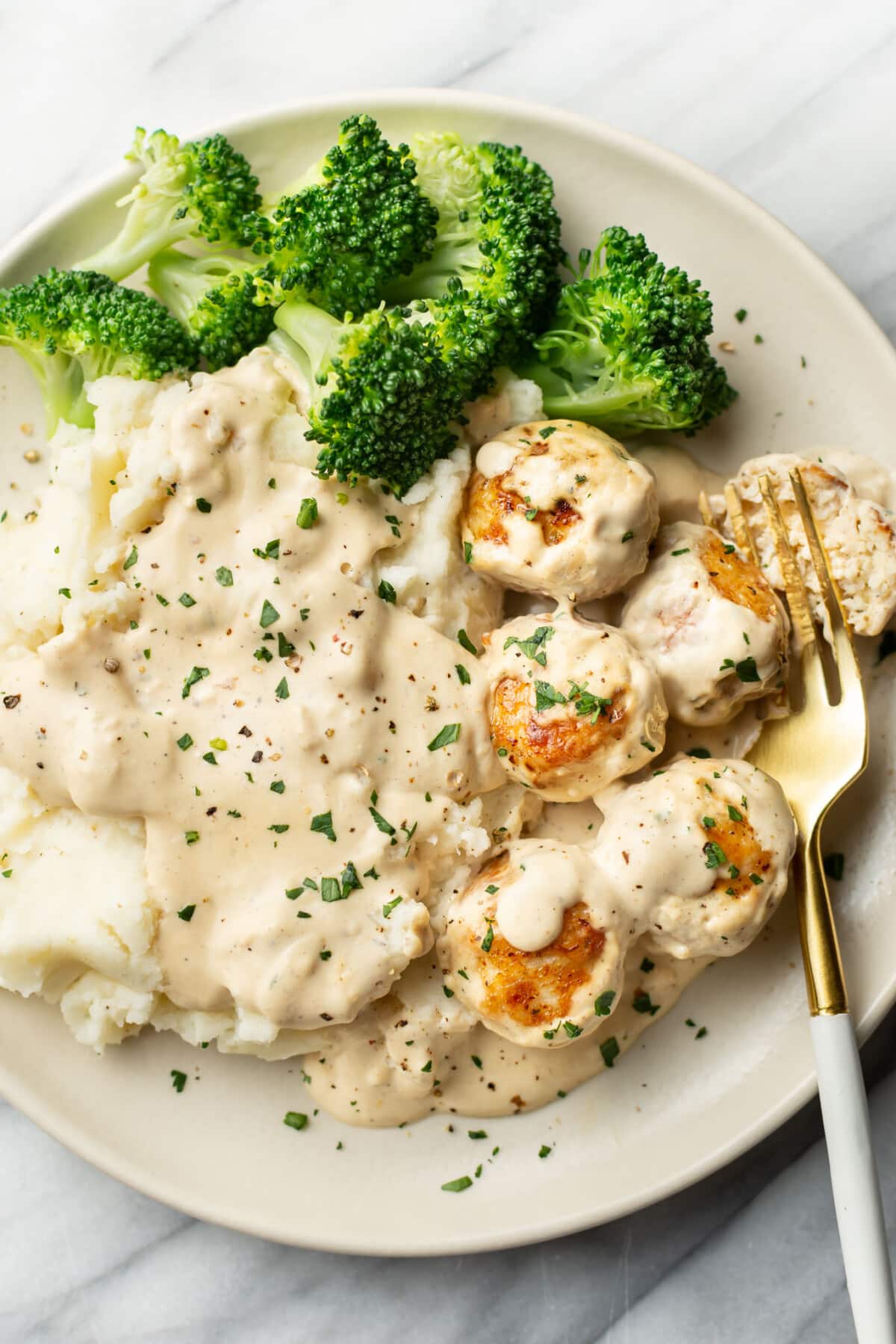 a plate with ranch chicken meatballs, mashed potatoes, broccoli, and a fork