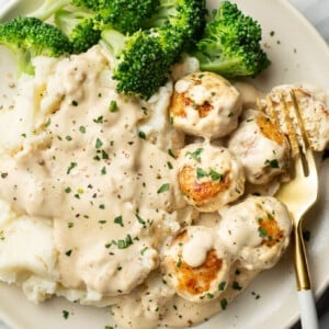 a plate with ranch chicken meatballs, mashed potatoes, broccoli, and a fork