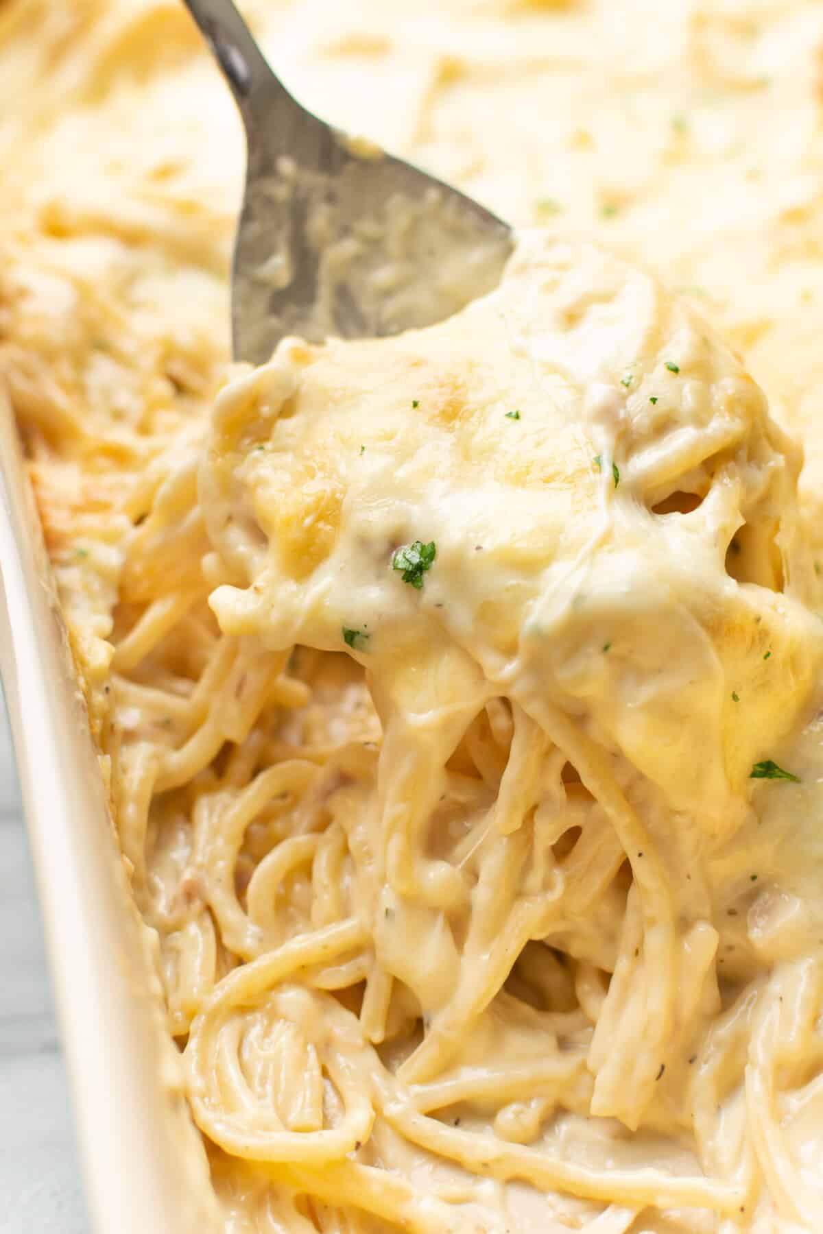 closeup of a casserole dish with ranch chicken spaghetti and a serving spoon